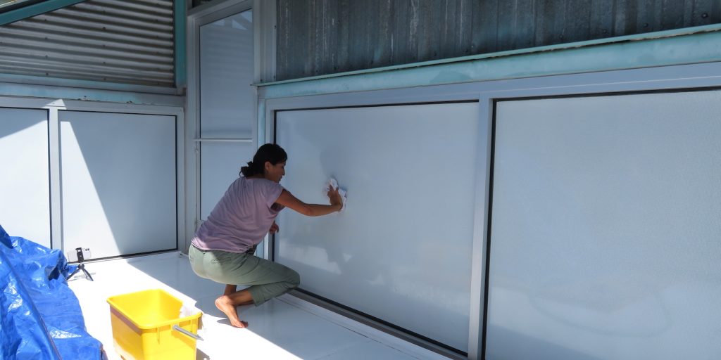 Colleen applies vinyl film to the exterior of a window.